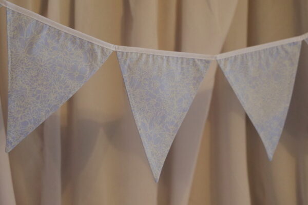 Light blue material triangle bunting with a flower pattern in white